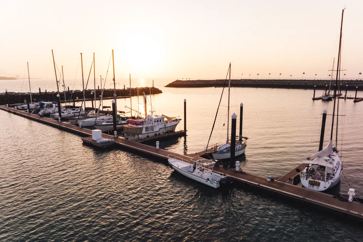Sailboats and motor yachts moored along the docks at Vista Mar Marina at sunset